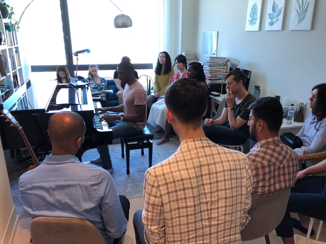 large group of students around student performing at piano